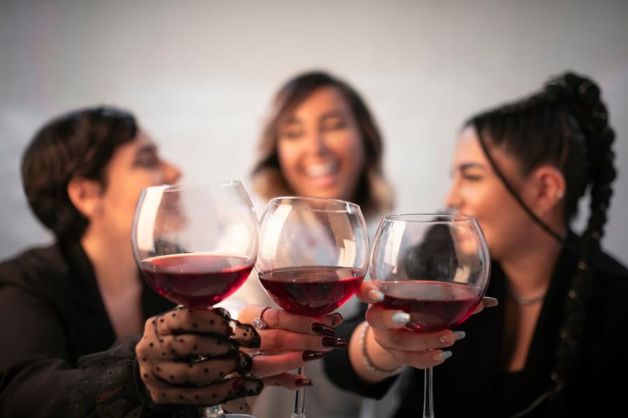 Drie vriendinnen proosten met een glas rode wijn