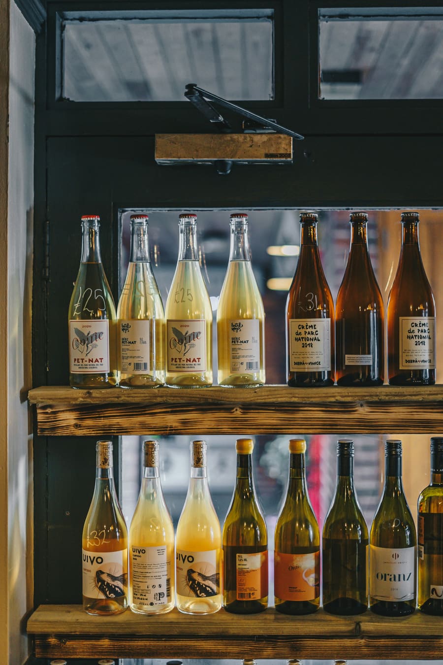 Een houten schap vol flessen natuurwijn